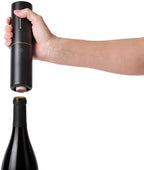 Hand using a black electric wine opener on a white background