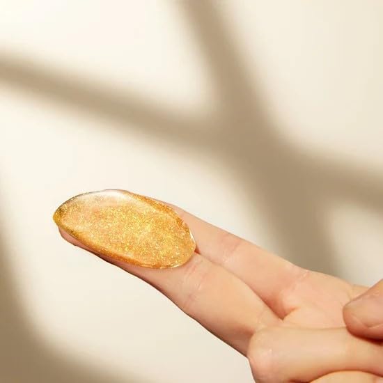 Gold glittery nail polish on a finger against a neutral background