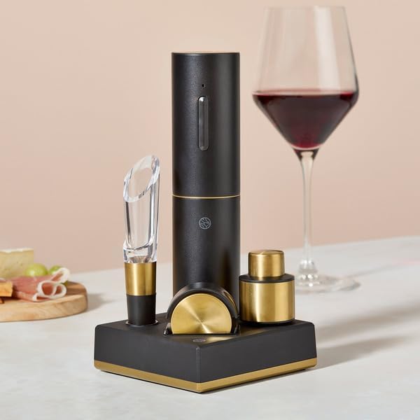 Black and gold wine opener set with a glass of red wine on a light background