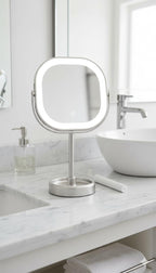 Luminous makeup mirror on a bathroom counter with sink and faucet in the background