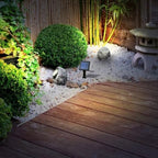 Small garden with wooden deck, plants, and a solar light