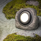 Rock-shaped outdoor light fixture on a mossy ground