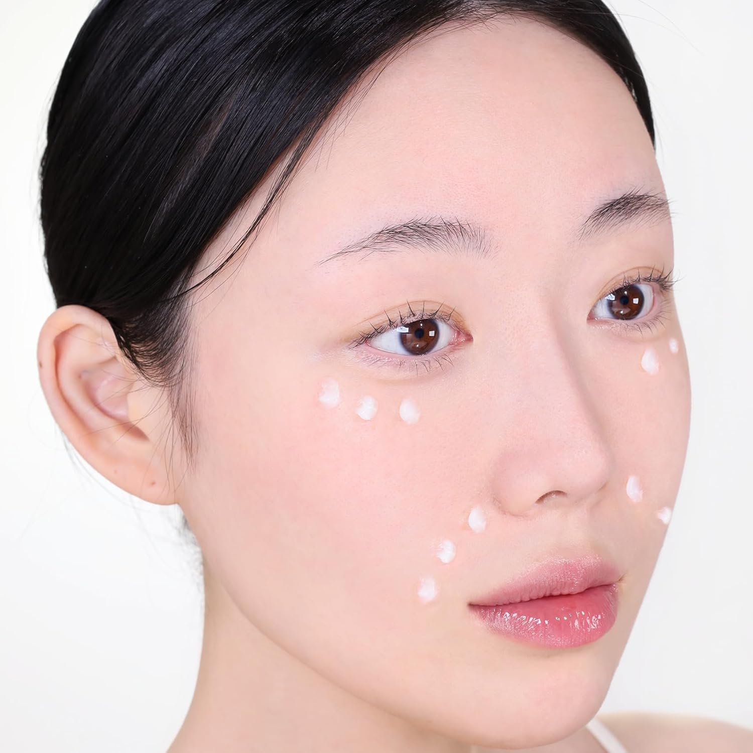 Close-up of a person's face with white dots on a plain background