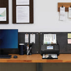 Desk setup with a scanner, mug, and office supplies against a wall with pinned documents.