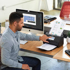 Man using an Epson scanner at a desk with a computer in the background