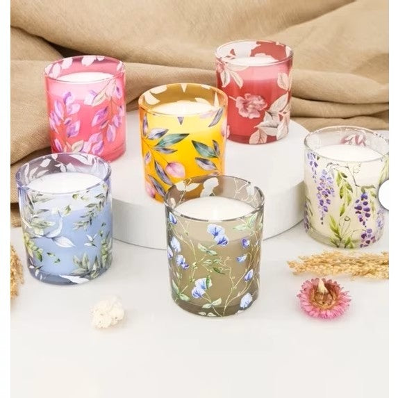 Set of floral-patterned candles on a white surface with a beige fabric background